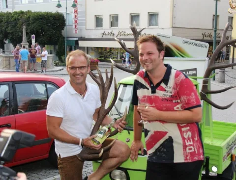 Zwei Männer am grünen Kleintransporter auf dem Platz