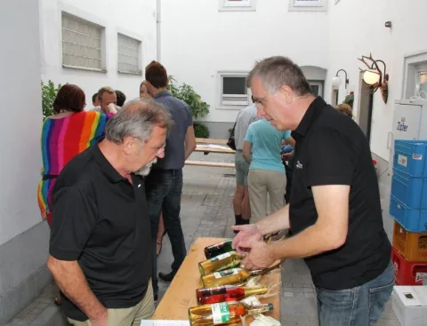 Besucher an einem Tisch mit Weinflaschen