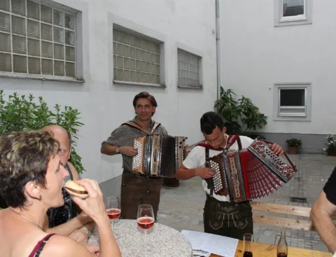 Zwei Musiker spielen neben Gästen an einem Tisch