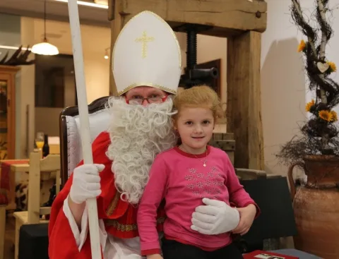 Der Nikolaus mit einem Mädchen auf dem Arm im Verkaufsraum