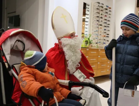 Der Nikolaus beugt sich zu einem Kind im Kinderwagen