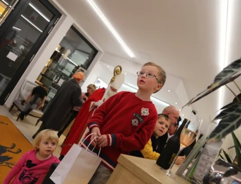 Ein Junge mit Geschenktüte, dahinter Erwachsene