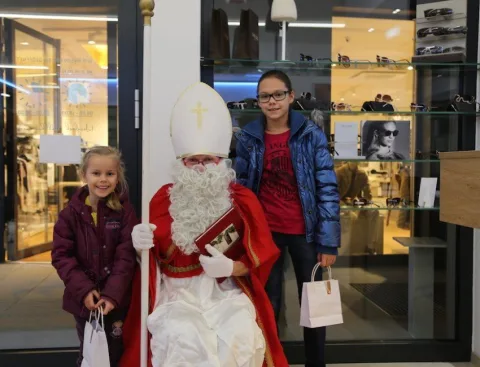 Ein Mädchen mit Geschenktüte neben dem Nikolaus