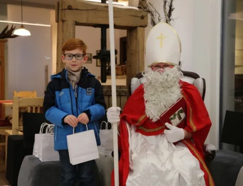 Ein Junge mit Geschenktüte neben dem Nikolaus