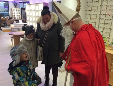 Der Nikolaus beugt sich zu einem Kind, daneben die Mutter