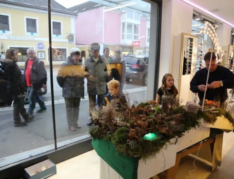 Kinder an einer Weihnachtsdekoration im Schaufenster, draußen Passanten