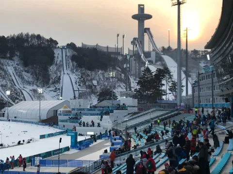 Die Skisprungschanzen im Abendlicht, davor die Zuschauertribünen