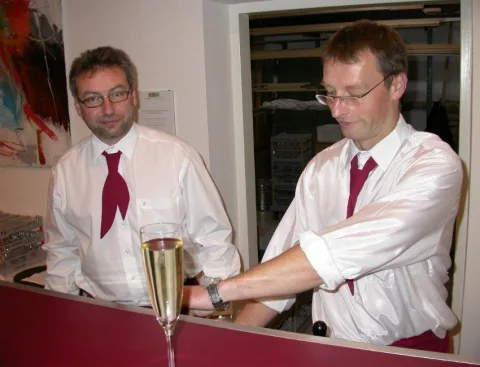 Zwei Kellner schenken Sekt aus