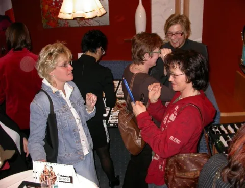 Besucherinnen mit Gläsern an einem Stehtisch