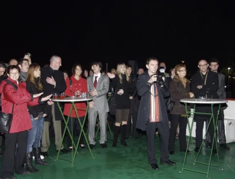 Gäste an Stehtischen auf dem Oberdeck bei Nacht