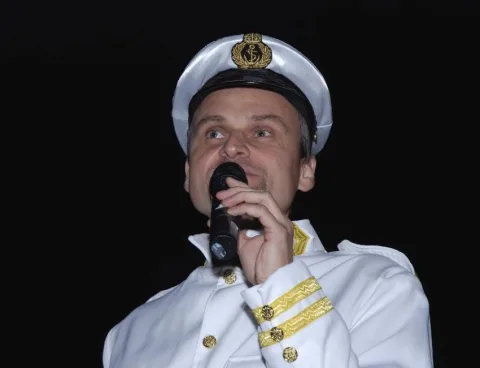 Ein Darsteller in Kapitänsuniform singt ins Mikrofon