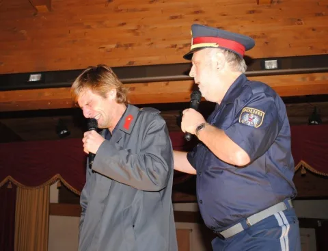 Ein Mann in Polizeiuniform steht neben einem anderen Mann, der ein Mikrofon hält