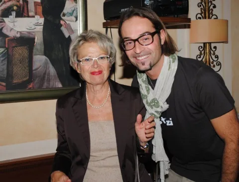 Ein Mann und eine Frau posieren für ein Foto, wobei der Mann ein T-Shirt mit der Aufschrift „nzi“ trägt