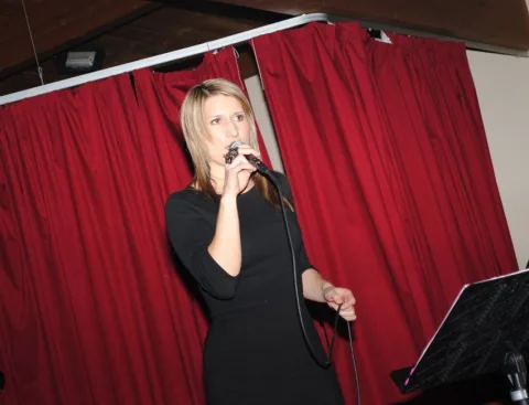 Eine Frau in einem schwarzen Kleid singt in ein Mikrofon