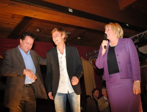 Eine Frau in einem lila Anzug singt in ein Mikrofon