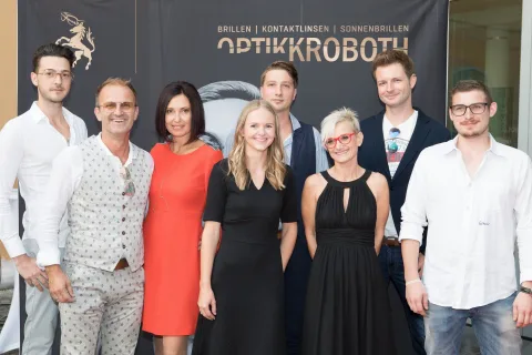 Eine Gruppe von Menschen posiert für ein Foto vor einem Schild mit der Aufschrift „Optikkrobotu“