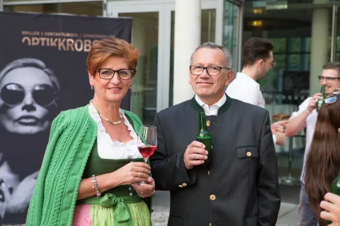 Ein Mann und eine Frau stehen nebeneinander und halten Weingläser.