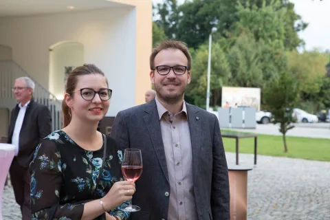 Ein Mann und eine Frau stehen nebeneinander und halten Weingläser.