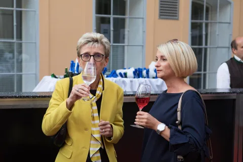 Zwei Frauen stehen nebeneinander und halten Weingläser.
