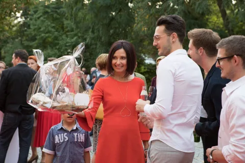 Eine Frau in einem roten Kleid steht in einer Menschenmenge und hält einen Korb.