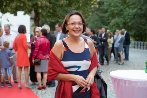 Eine Frau steht vor einer Menschenmenge auf einem roten Teppich.
