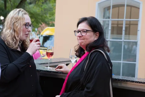 Zwei Frauen stehen nebeneinander und trinken Wein.