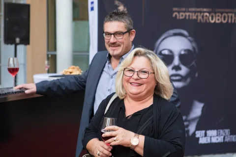 Ein Mann und eine Frau stehen nebeneinander und halten Weingläser.