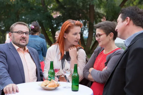 Eine Gruppe von Leuten steht mit Bierflaschen um einen Tisch herum.