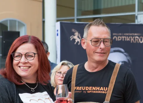 Ein Mann und eine Frau stehen nebeneinander und halten Weingläser.
