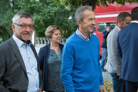 Eine Gruppe von Menschen steht nebeneinander vor einem roten Bus.