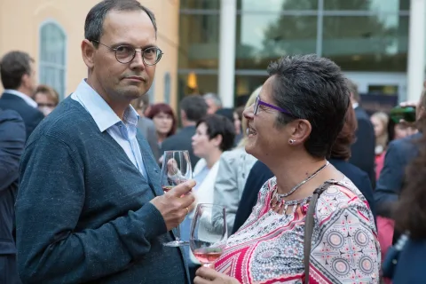 Ein Mann und eine Frau unterhalten sich, während sie Weingläser in den Händen halten.