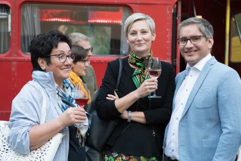 Eine Gruppe von Menschen steht nebeneinander vor einem roten Bus.
