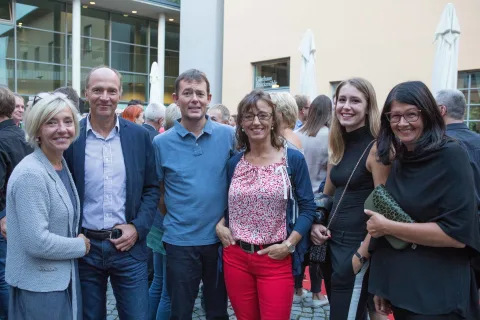 Eine Gruppe von Menschen posiert vor einem Gebäude für ein Foto.