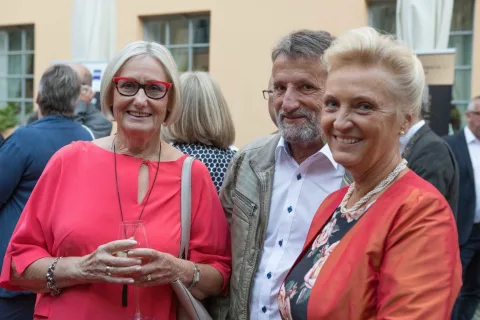Eine Gruppe von Menschen posiert nebeneinander stehend für ein Foto.