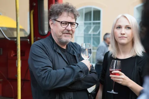 Ein Mann und eine Frau stehen nebeneinander und halten Weingläser in der Hand.