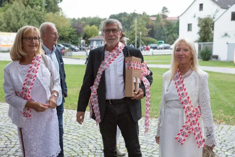 Eine Gruppe von Menschen steht nebeneinander auf einer Kopfsteinpflasterstraße.