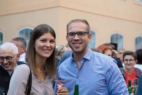 Ein Mann und eine Frau posieren mit Weingläsern in der Hand für ein Foto.