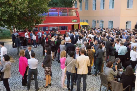Eine große Gruppe von Menschen steht vor einem roten Doppeldeckerbus.