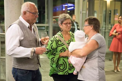 Ein Mann und zwei Frauen unterhalten sich, während eine Frau ein Baby hält.