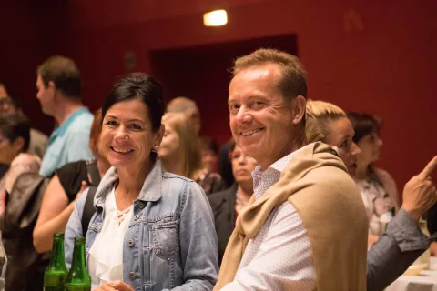 Ein Mann und eine Frau stehen in einem überfüllten Raum nebeneinander.