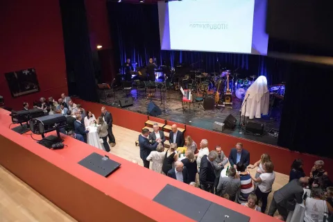 Eine Gruppe von Menschen steht auf einer Bühne vor einer großen Leinwand.