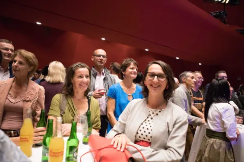 Eine Gruppe von Leuten sitzt mit Getränken an einem Tisch.