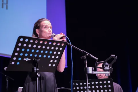 Eine Frau singt auf einer Bühne in ein Mikrofon.