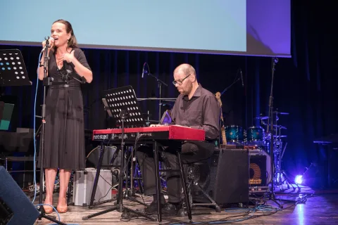 Auf der Bühne spielt ein Mann Keyboard und eine Frau singt.