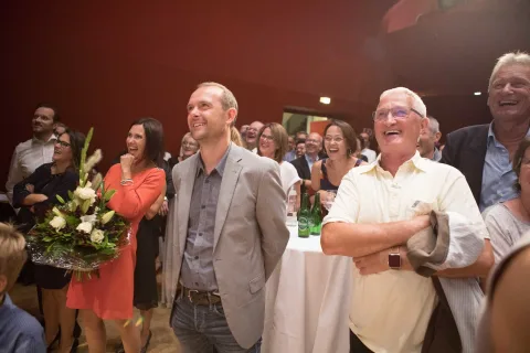 Eine Gruppe von Menschen steht in einem Raum und lacht.