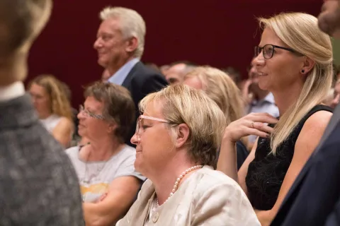 Eine Gruppe von Leuten sitzt in einem Raum und sieht sich eine Präsentation an.