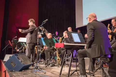 Ein Mann spielt auf einer Bühne vor einem Orchester Keyboard.
