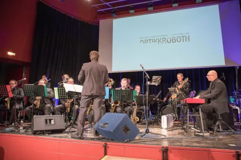 Ein Mann steht auf einer Bühne und leitet ein Orchester.