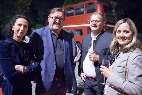 Eine Gruppe von Menschen posiert für ein Foto vor einem roten Doppeldeckerbus.