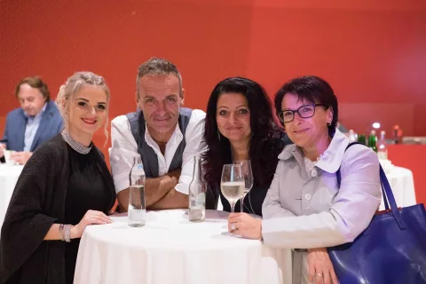 Eine Gruppe von Menschen sitzt mit Weingläsern an einem Tisch.